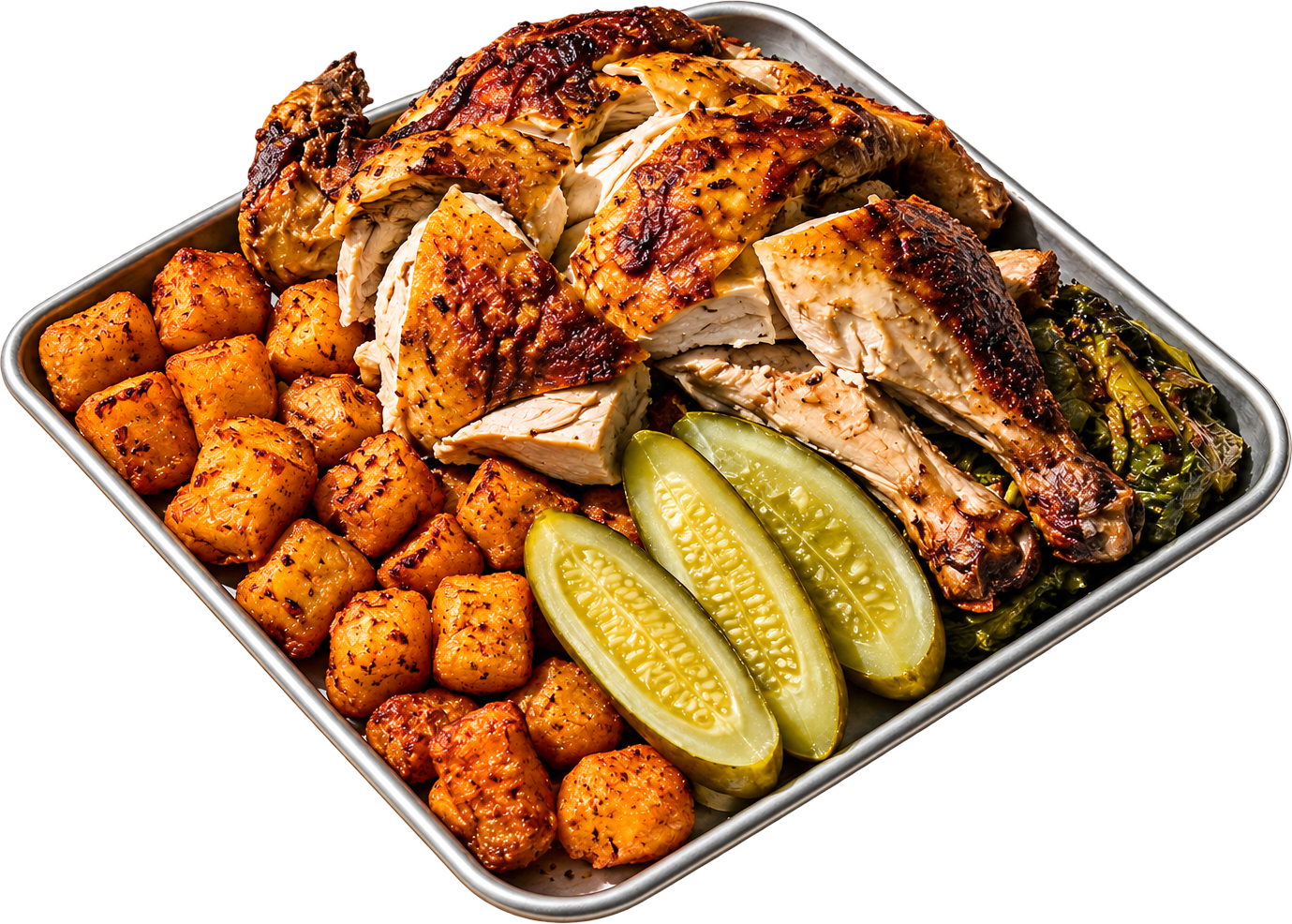 A rotisserie chicken on a metal tray with crispy potatoes, pickles and charred greens