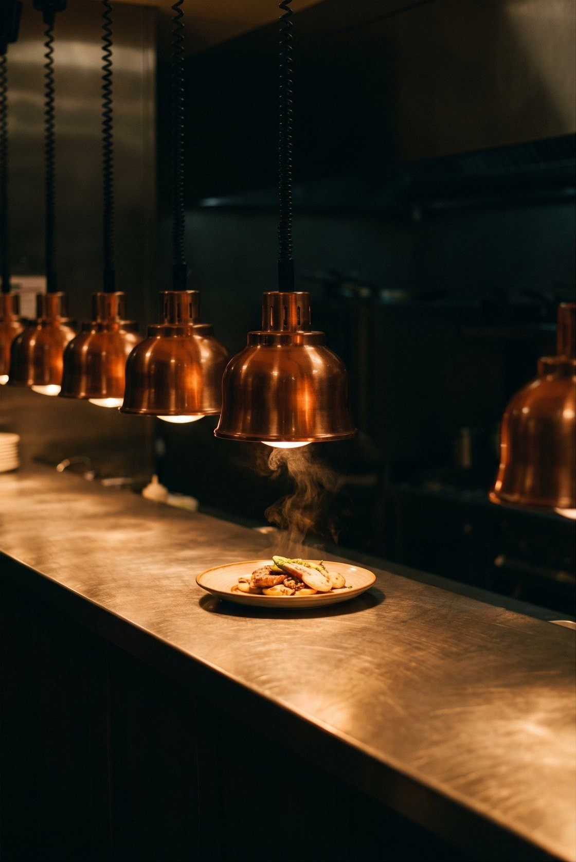 A finished plate waiting under the copper heat lamps of the pass, steam still rising